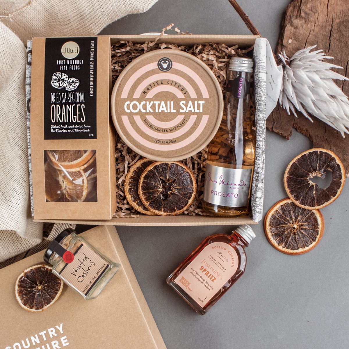 Photo of our spritz cocktail kit inside an ecofriendly gift box, and a country backdrop.